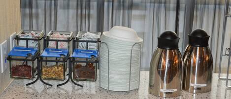A breakfast bar with various food containers and thermos bottles.