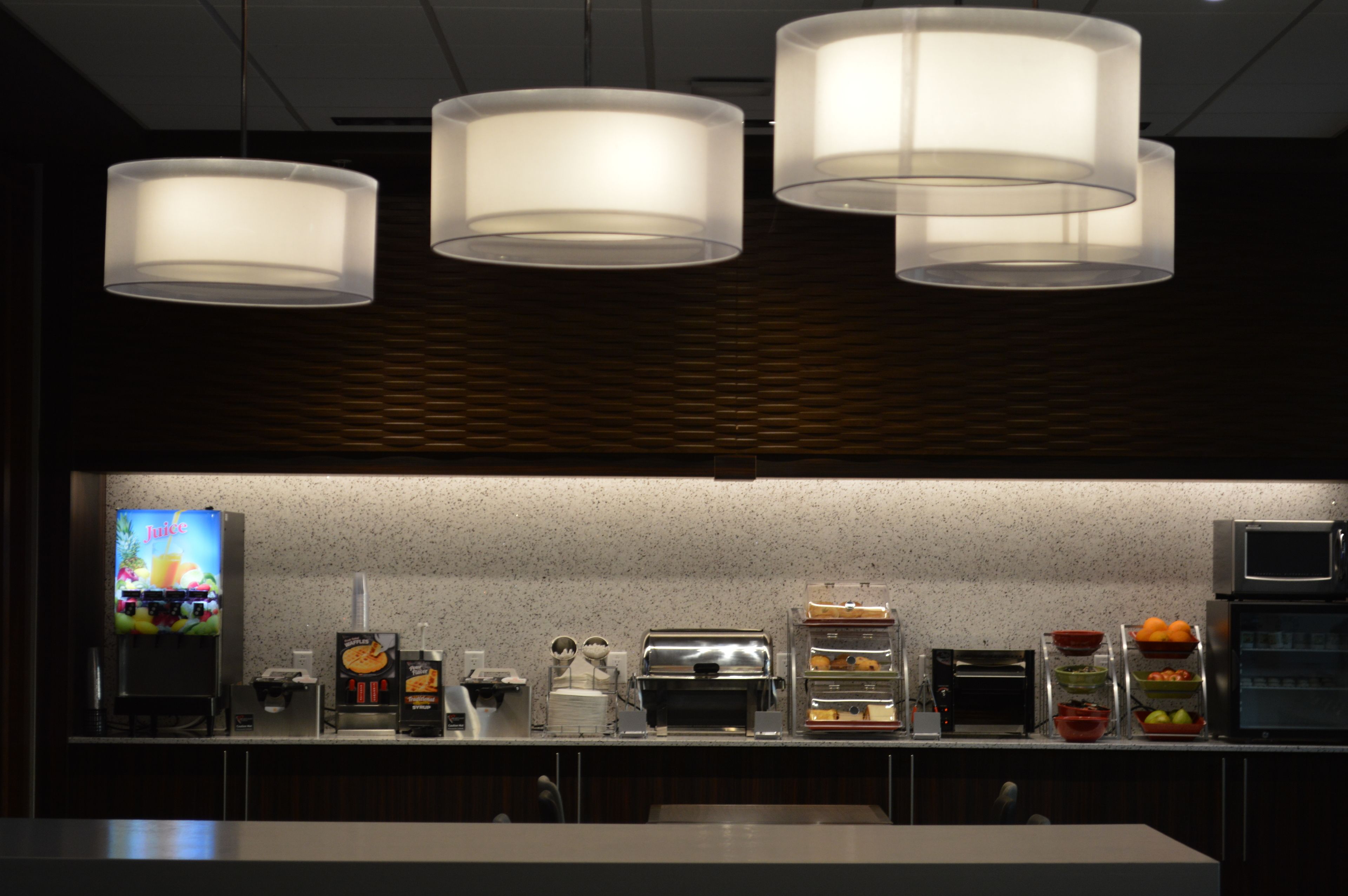 A modern kitchen with three pendant lights, a coffee machine, a toaster, and a refrigerator.