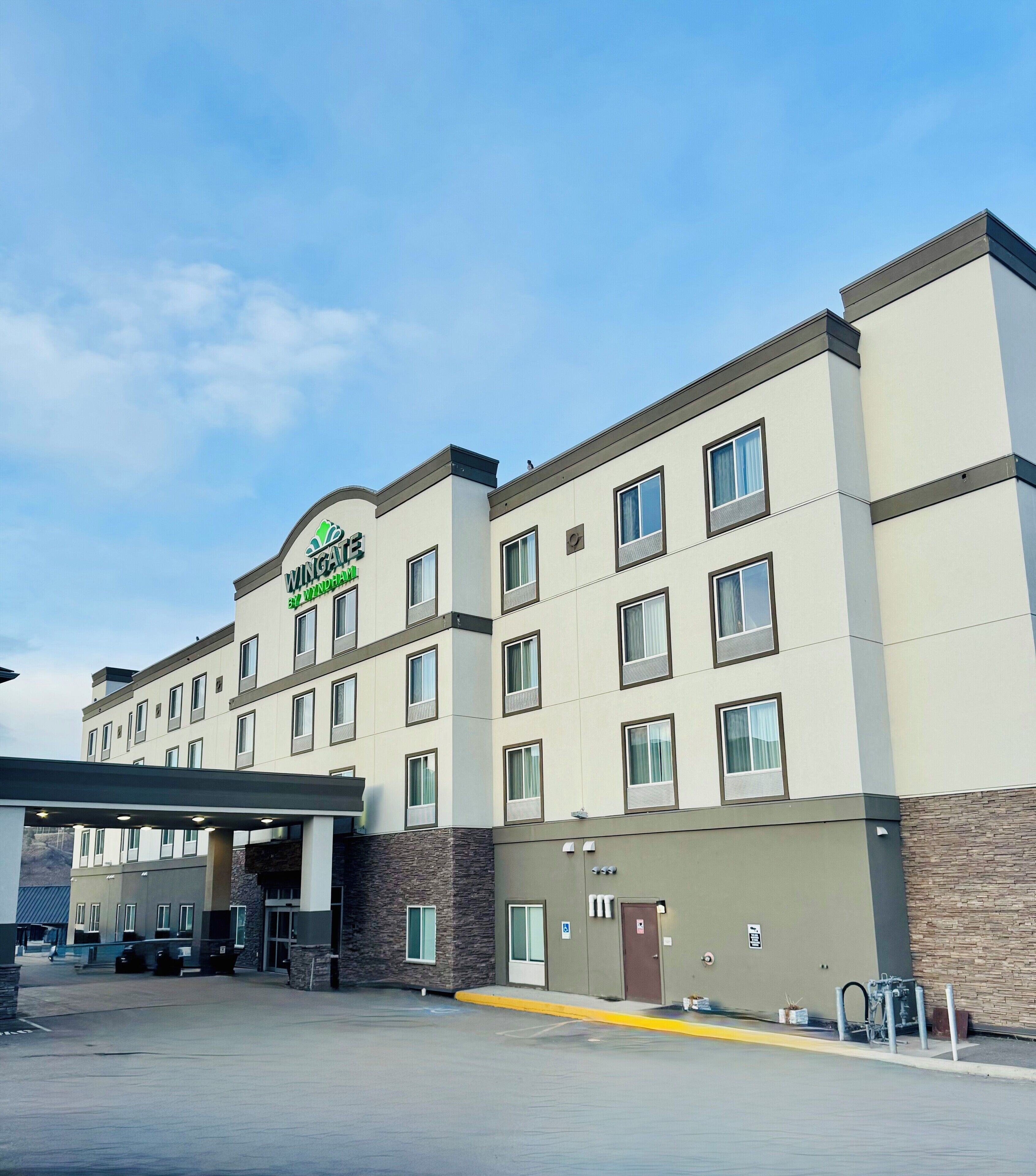 A multi-story hotel with a flat roof and a large parking lot in front.