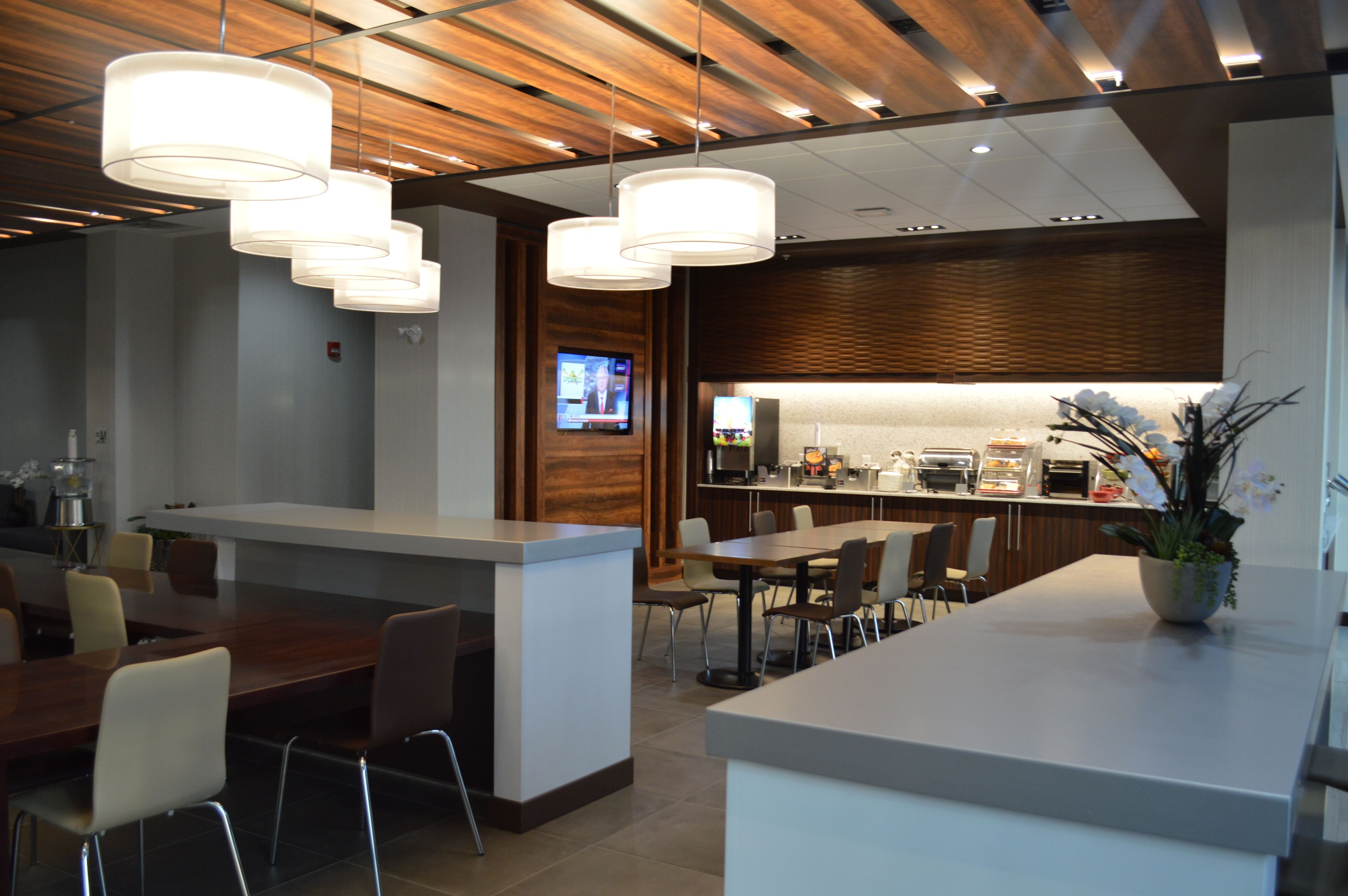Un restaurant moderne avec un plafond en bois, des luminaires suspendus, un comptoir et un écran de télévision.