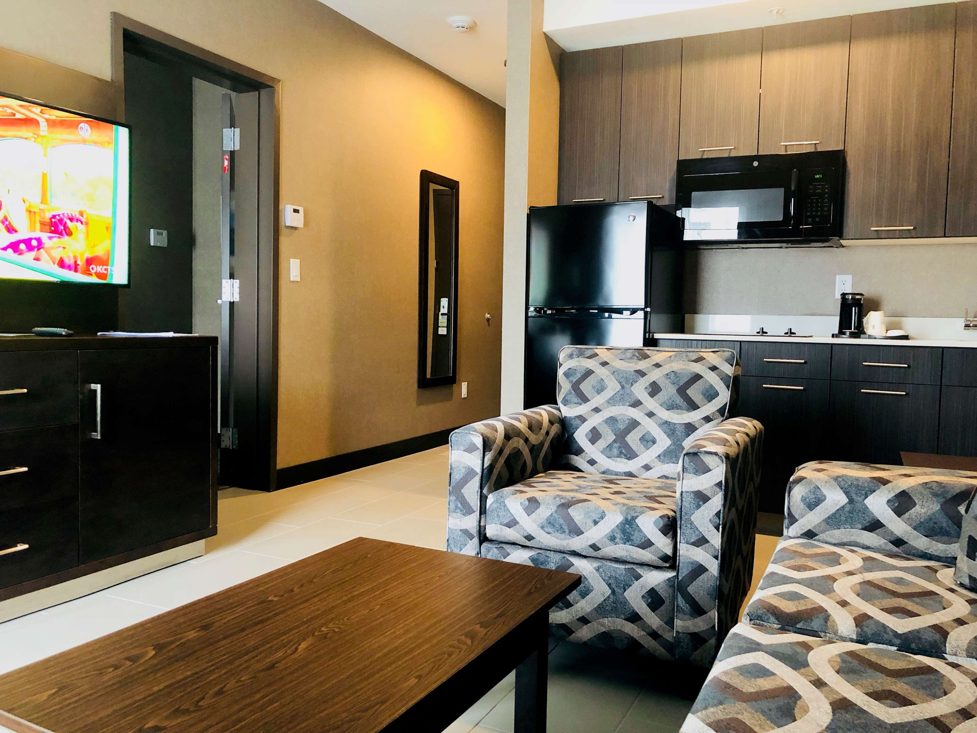 Un espacio habitable pequeño con kitchenette, televisor y sillones estampados.