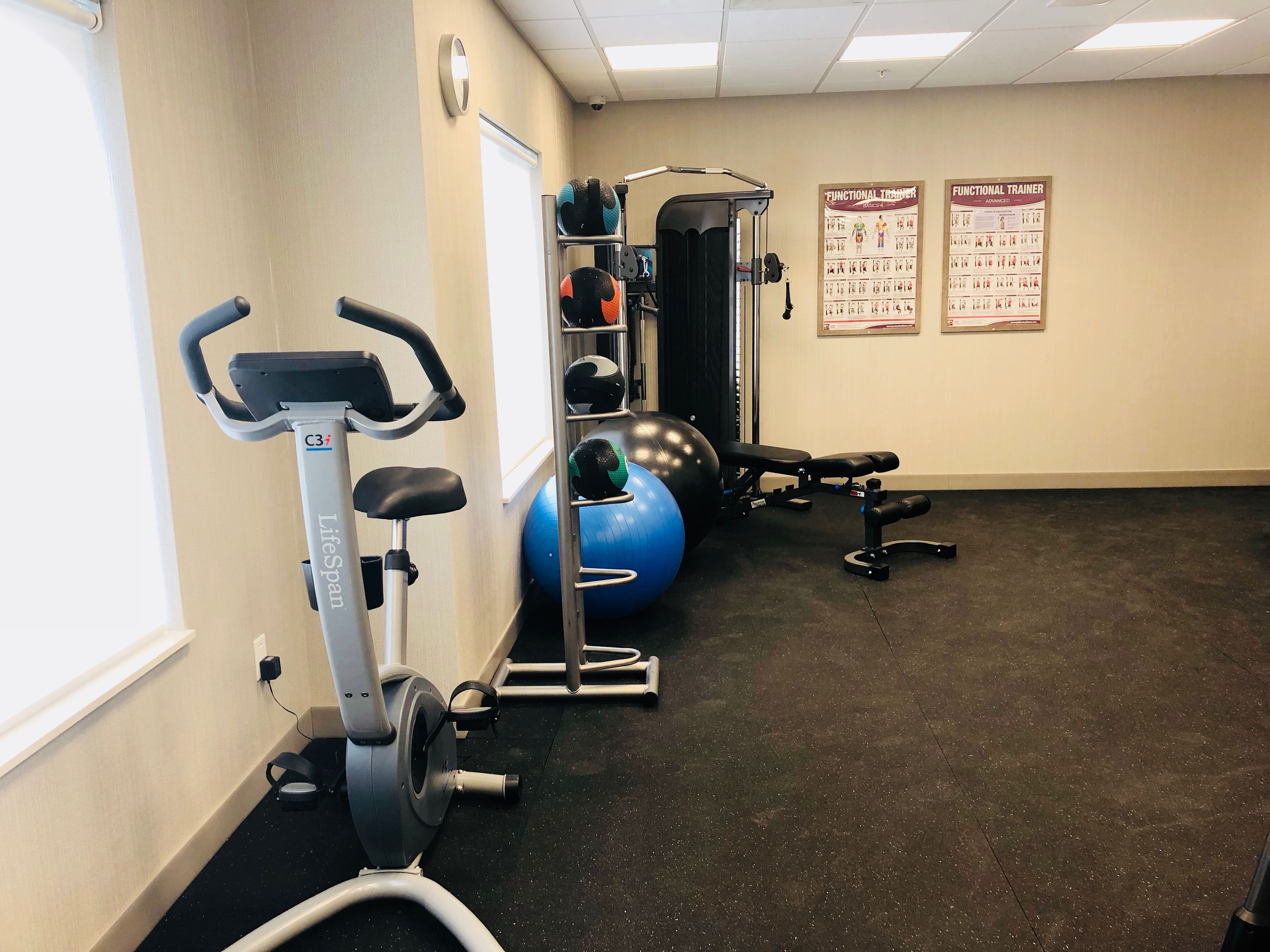 A gym with exercise equipment including a treadmill, weight machines, and exercise balls.