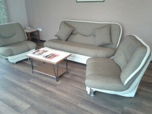 Un salon comprenant un canapé, deux fauteuils, une table basse et une petite table d’appoint avec un téléphone.