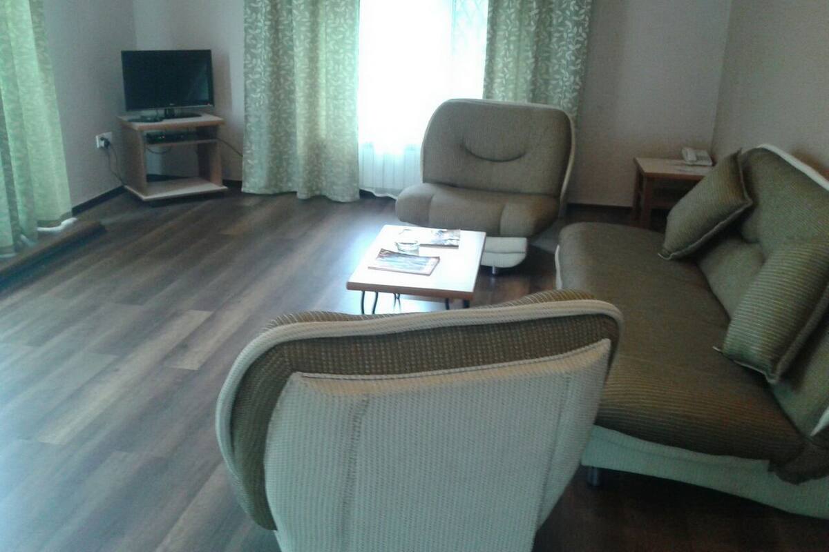 Una sala de estar con sofá, sillón, mesa de centro y televisor sobre un mueble.