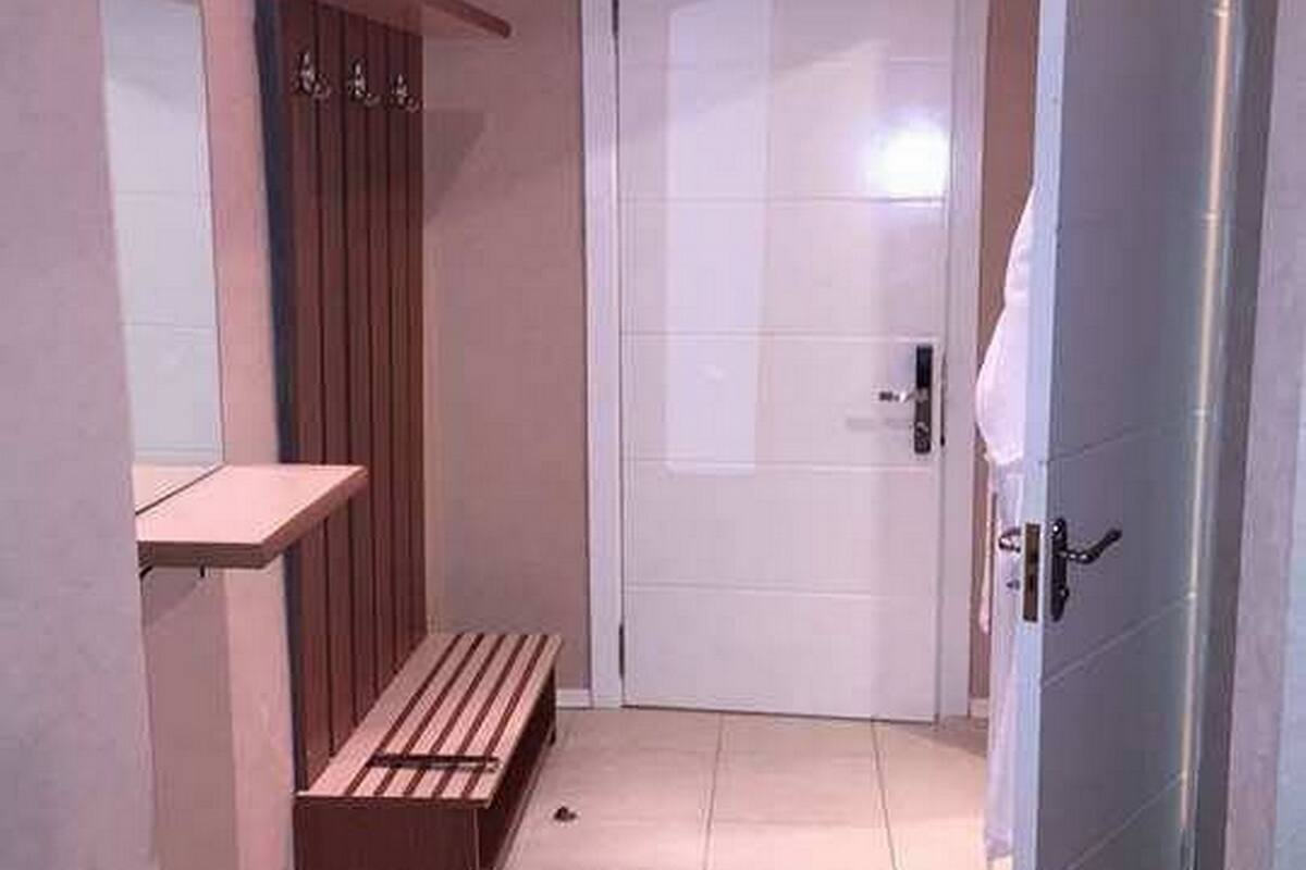 Un baño pequeño y estrecho con un banco, un espejo y una puerta.
