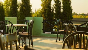Un patio al aire libre con mesas y sillas, rodeado de vegetación y árboles.