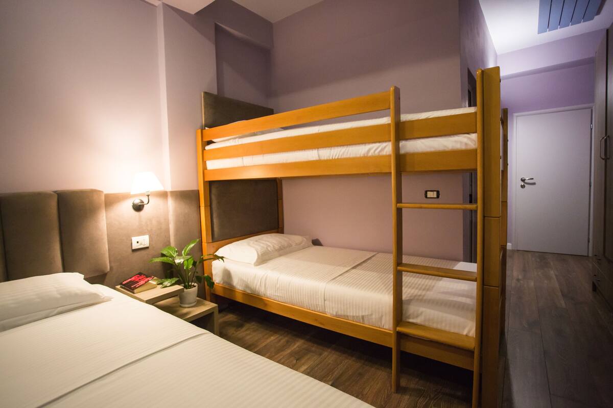A bunk bed room with a bedside table, a lamp, and a plant.