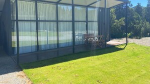 A modern glass structure with a covered patio area, surrounded by a well-maintained lawn and trees. - Cabanas Duendes del Maiten (San Carlos de Bariloche)
