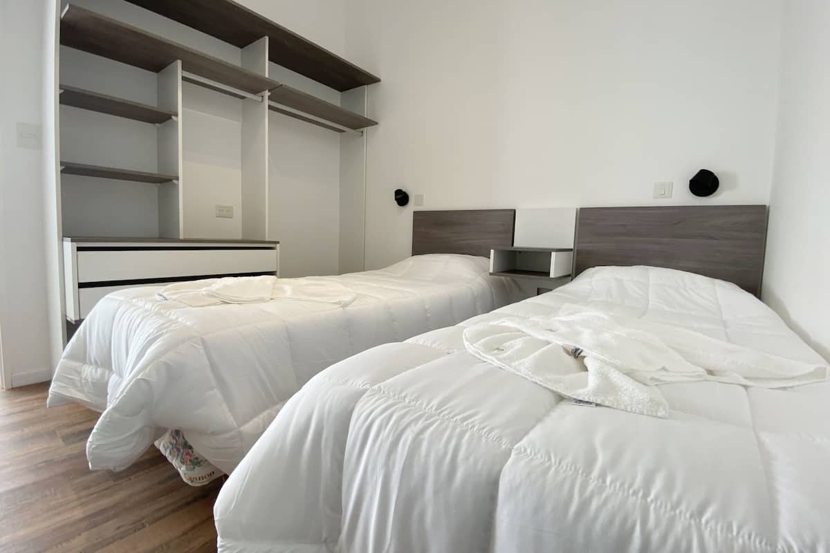 A bedroom with two beds, a dresser, and a built-in wardrobe.