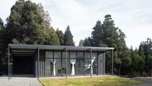 A modern building with a covered outdoor area, large windows, and a gravel driveway. - Cabanas Duendes del Maiten (San Carlos de Bariloche)