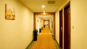 A hotel hallway with a carpeted floor, doors on both sides, and a painting on the left wall. - GreenTree Inn ShenZhen Huanggang Port South Futian Road Express Hotel (Shenzhen)