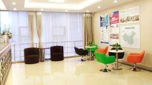 A modern hotel lobby with a reception desk, several seating areas with chairs, and informational posters on the walls. - GreenTree Inn ShenZhen Huanggang Port South Futian Road Express Hotel (Shenzhen)