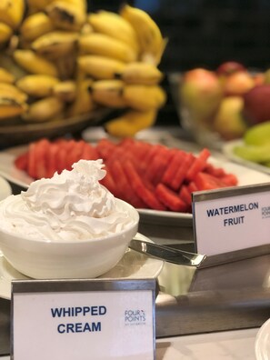 A dessert display with whipped cream, watermelon fruit, and bananas.