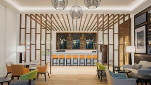 A modern lobby with a bar area, seating arrangements, and a decorative wooden partition.