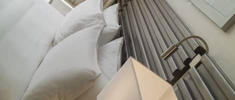 Une chambre d’hôtel moderne avec un lit bien fait, une tête de lit dotée de lattes verticales et une lampe fixée au mur.