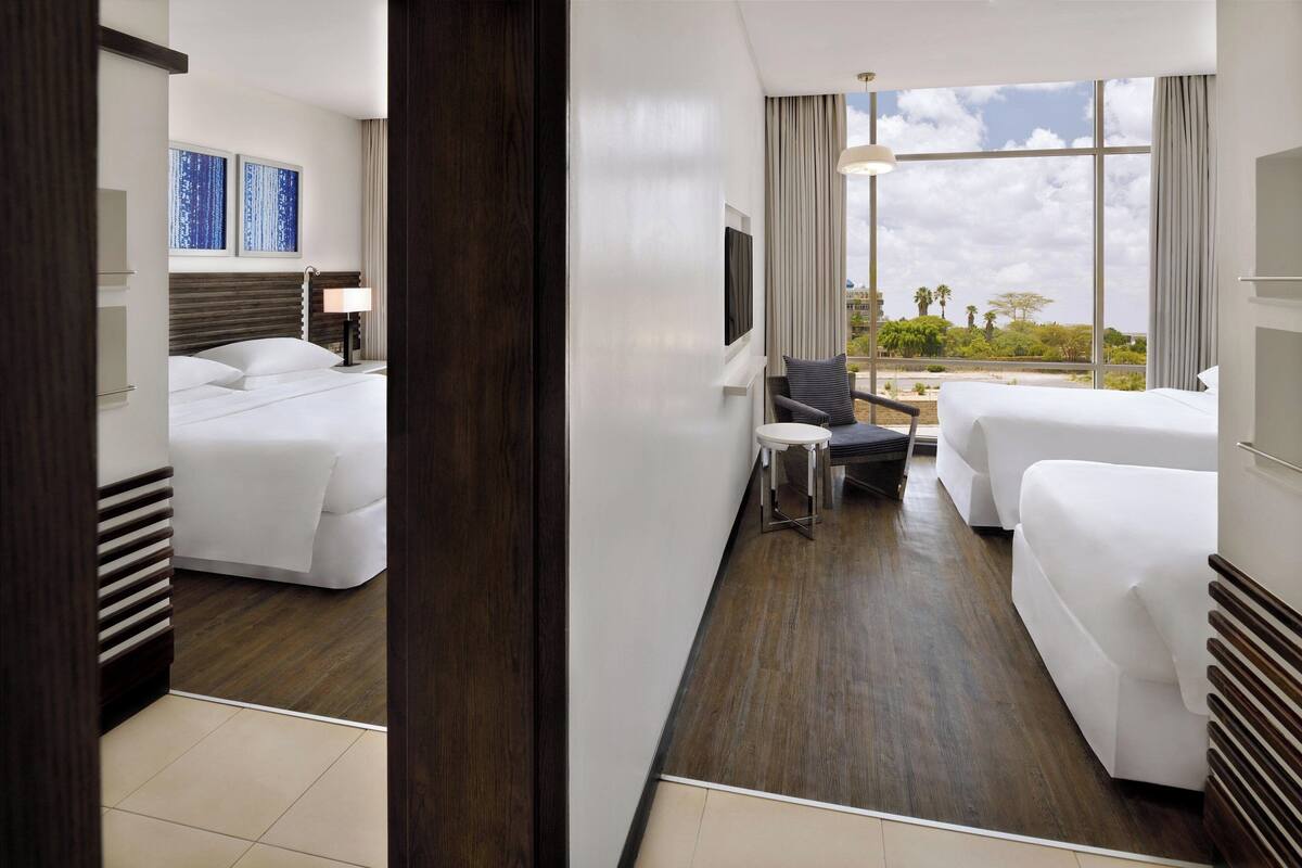 Habitación de hotel con cama, escritorio y sofá. Hay un televisor en la pared y una ventana con vistas al exterior.