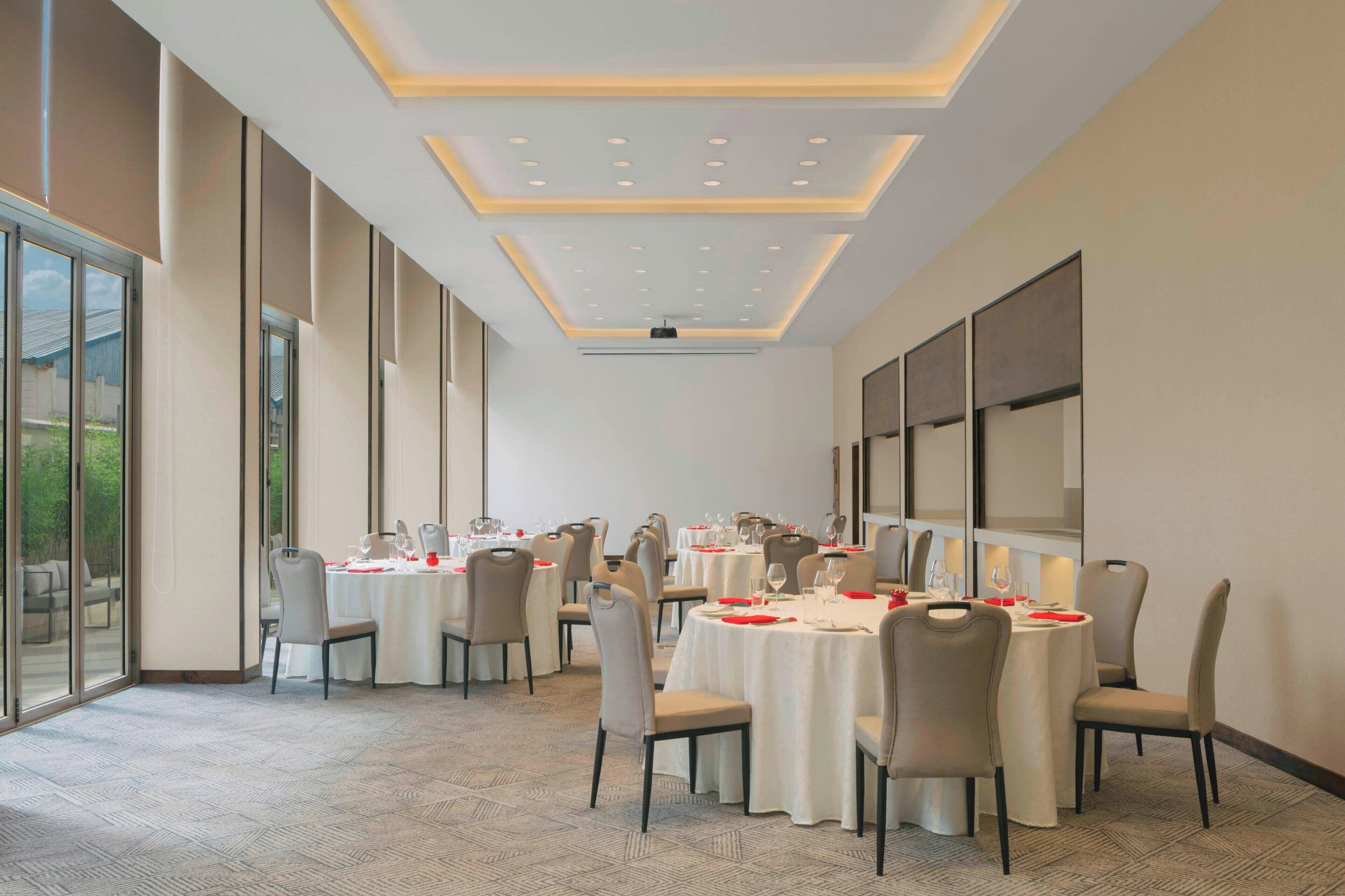 A conference room with round tables, chairs, and a large window.