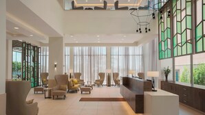 A spacious lobby with modern furniture, large windows, and a reception desk.