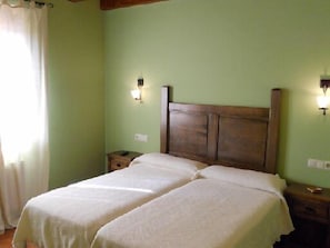 Ein Zimmer mit einem Doppelbett, zwei Nachttischen, einem Beistelltisch und einer Wandleuchte.