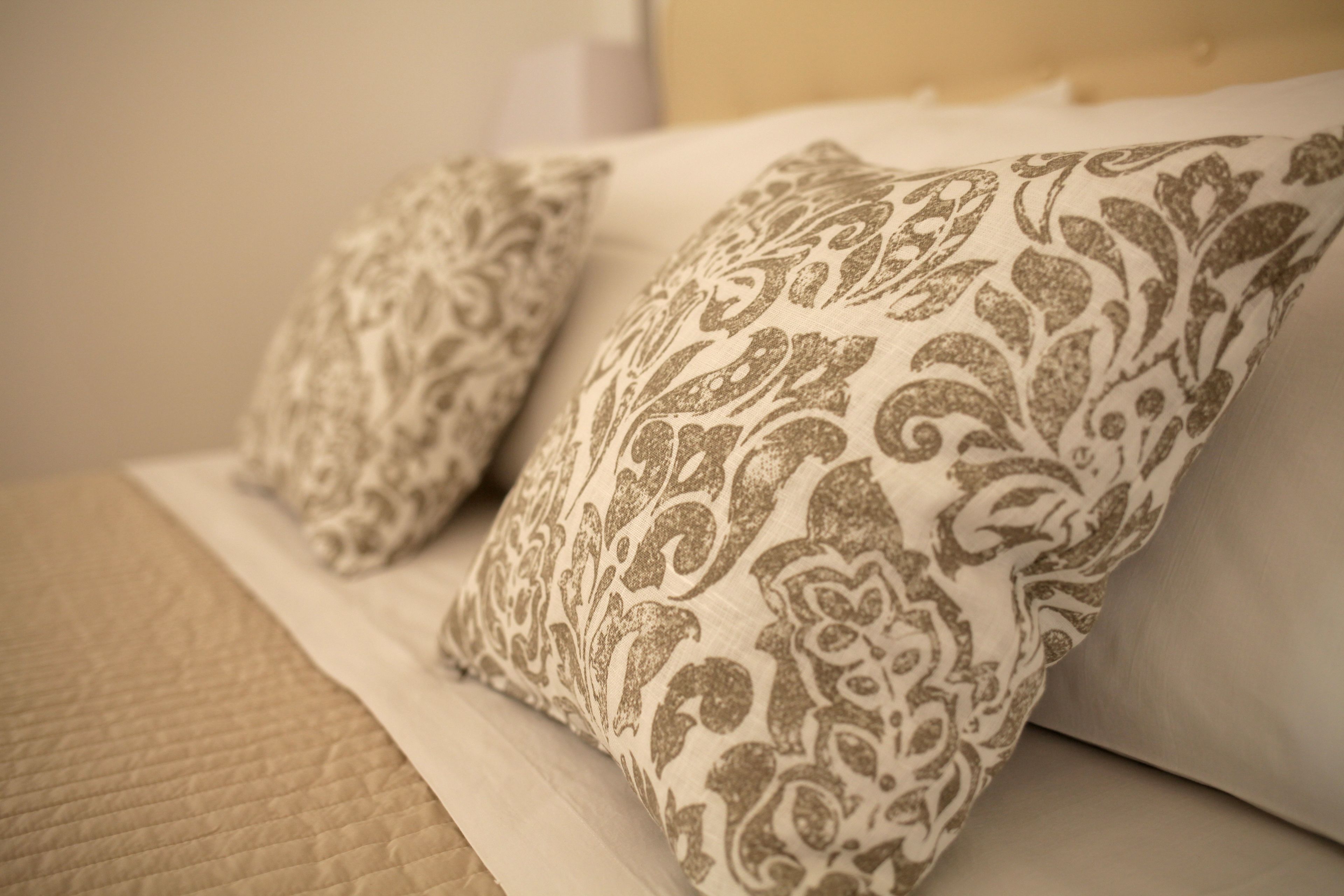 Una cama con dos almohadones decorativos de estampado paisley.