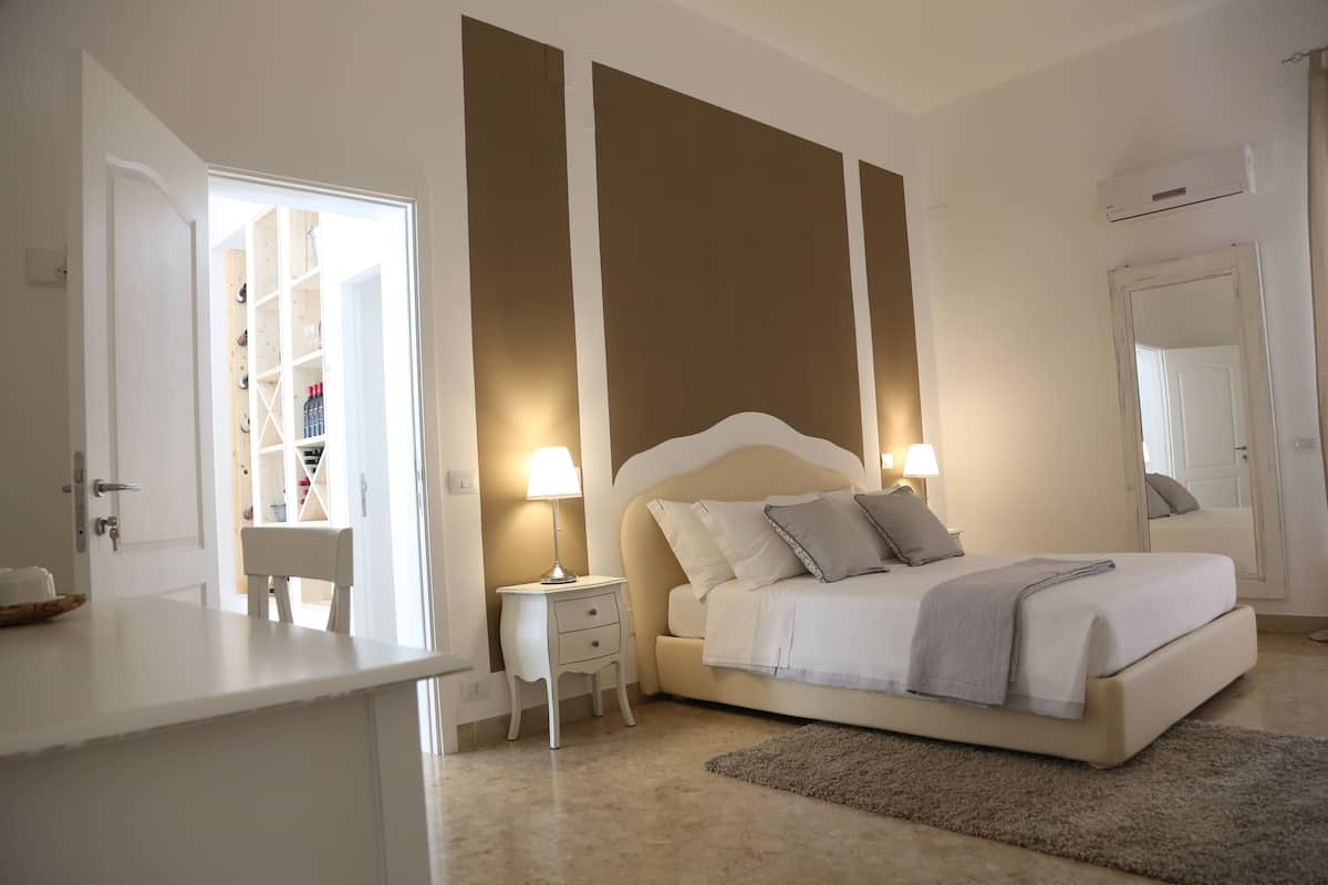 A bedroom with a bed, bedside tables, a nightstand, a wardrobe, and a mirror.