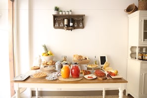 Un bufé de desayuno con diversos alimentos y bebidas, una botella de vino y un accesorio de iluminación fijado a la pared.