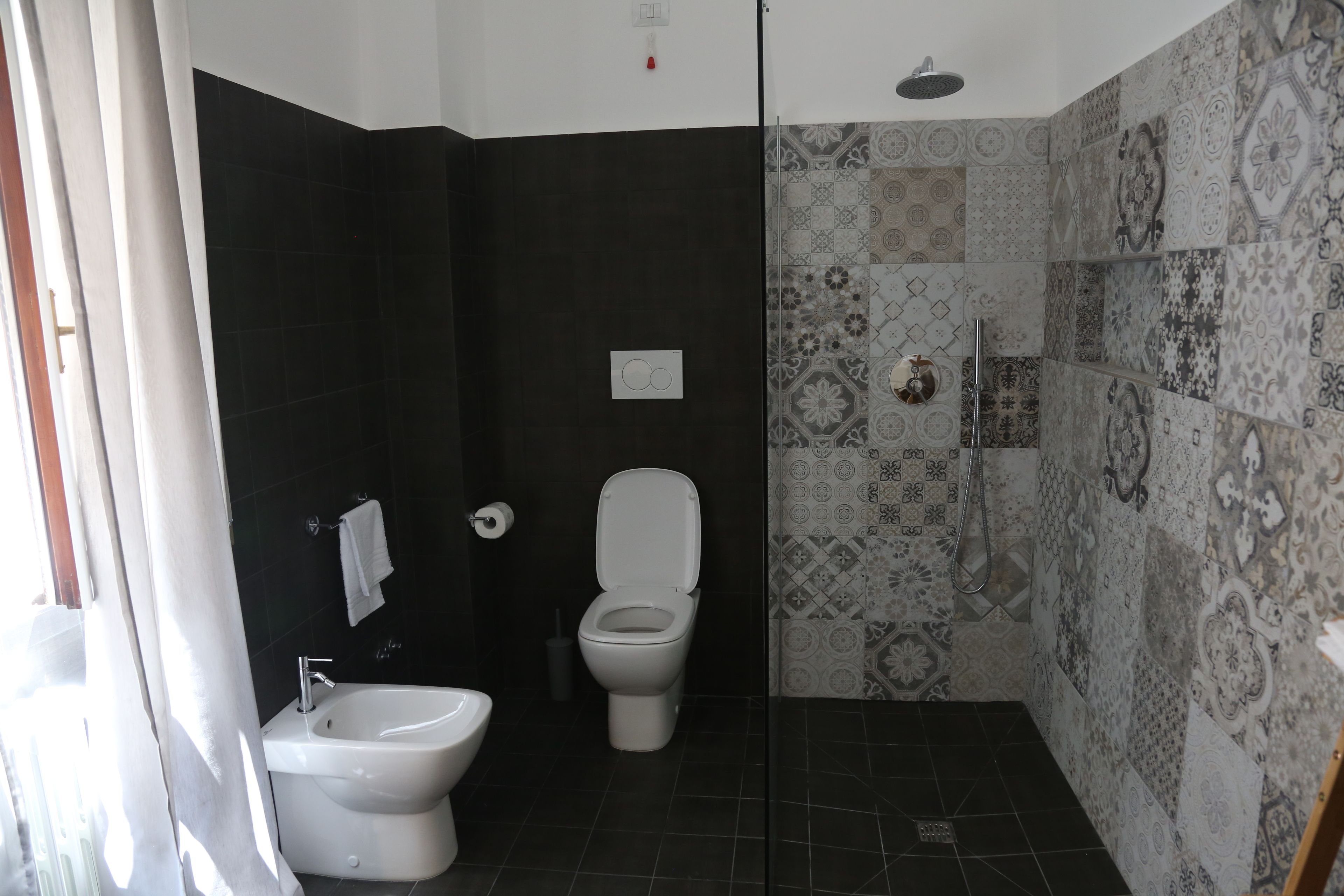 A bathroom with a bidet, toilet, and shower.