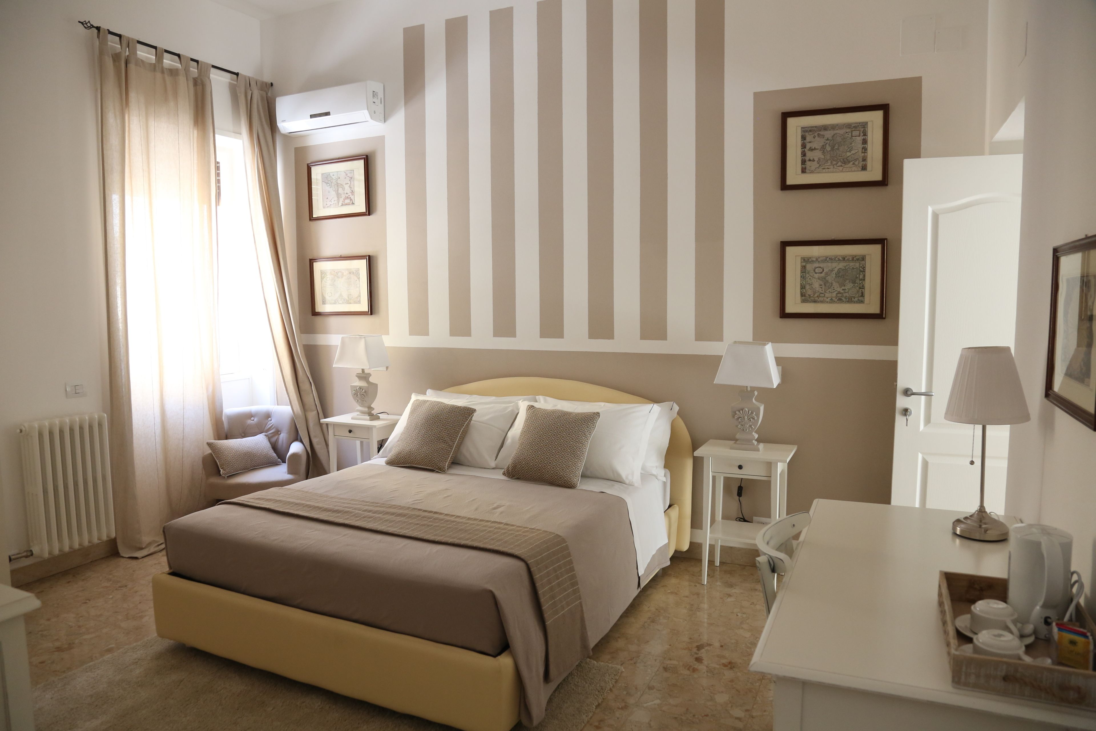 A hotel room with a large bed, bedside tables, a desk, and a radiator.