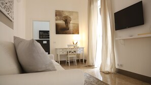 A modern hotel room with a white sofa, a desk with a chair, a flat-screen TV mounted on the wall, and a painting of an elephant. - Dimi House (Lecce)