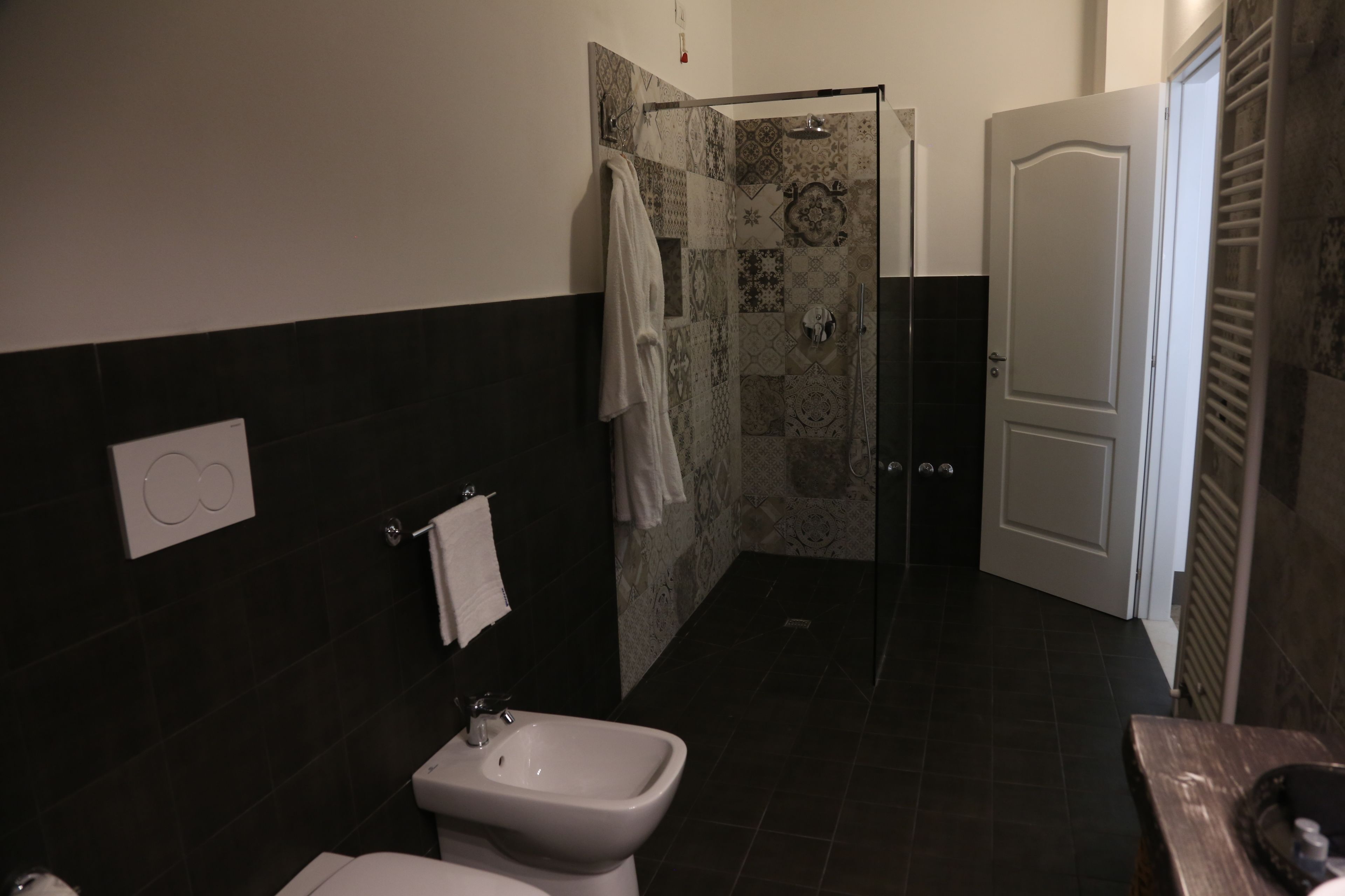 Un baño con bidé, inodoro, ducha con puerta de cristal y toallero.