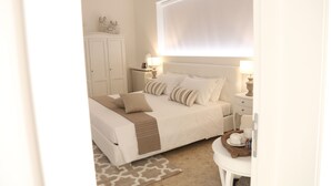 A bedroom with a bed, bedside tables, a wardrobe, and a window with blinds. - Dimi House (Lecce)