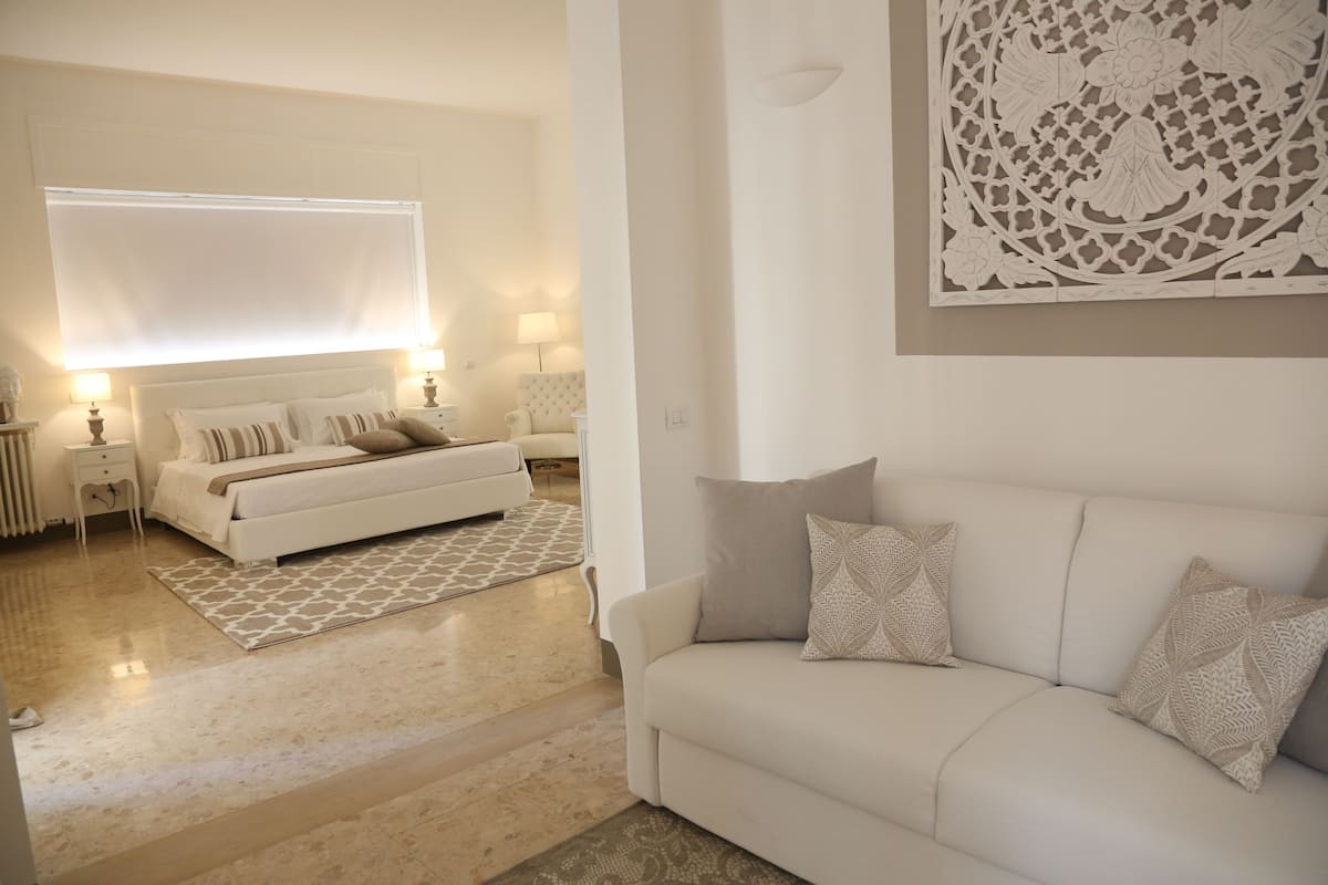 A modern bedroom with a bed, bedside tables, and a large window.