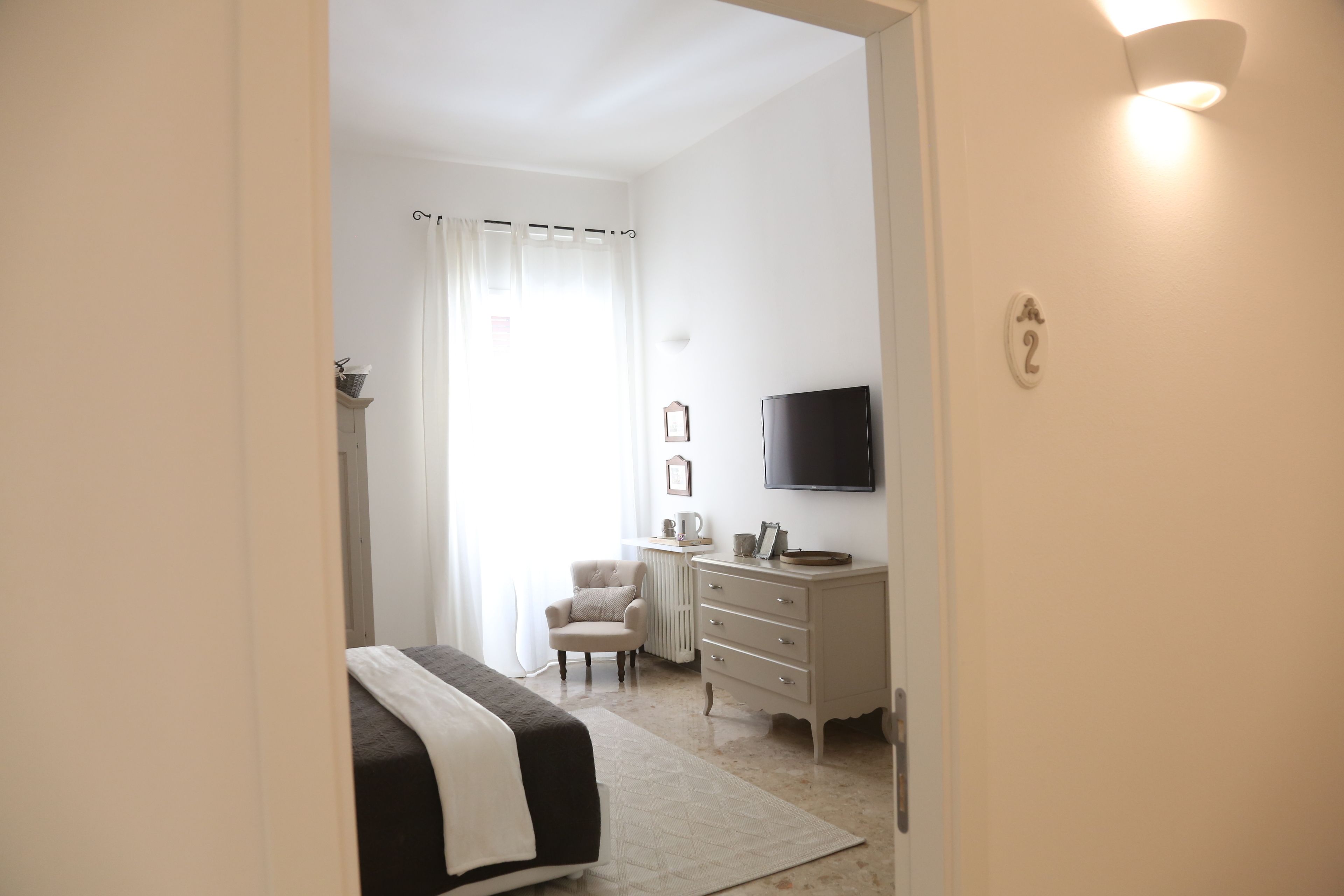 Une chambre à coucher comprenant un lit, une chaise, une commode, un téléviseur et un radiateur.