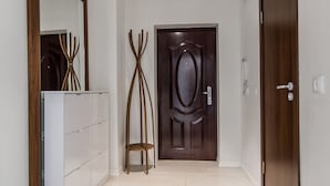 Un couloir avec une porte en bois, un porte-manteau et une armoire blanche.
