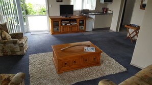 Una sala de estar con un sofá, una mesa de centro, una televisión y una zona de cocina.