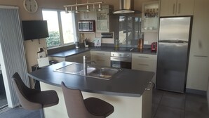 Una cocina moderna con una isla central, electrodomésticos de acero inoxidable y un comedor con dos sillas.