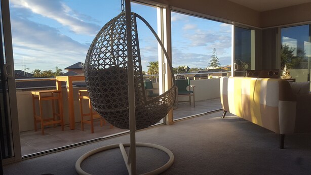 Un balcón con una silla colgante, un sofá y vistas del entorno.