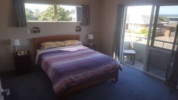 A bedroom with a bed, bedside lamps, a radio, and a view of the outside through a sliding door.