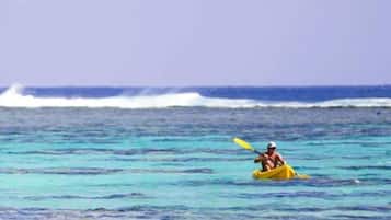 Una persona rema en kayak amarillo sobre un mar tranquilo.