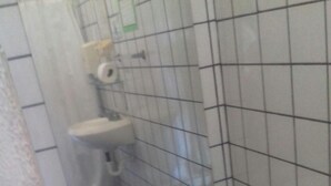 Un baño pequeño con un inodoro, un lavamanos y un cubo de basura verde.