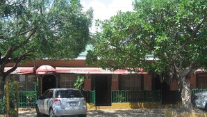 Un estacionamiento con un coche, un edificio con toldo rojo y un árbol.