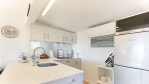 Eine moderne Küche mit weißen Schränken, einer Edelstahl-Spüle und einem integriertem Kühlschrank.