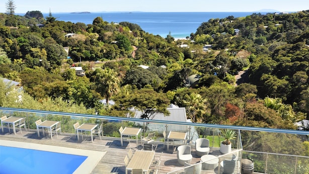 Ein Poolbereich mit Liegestühlen und Blick auf das Meer und die Hügel.