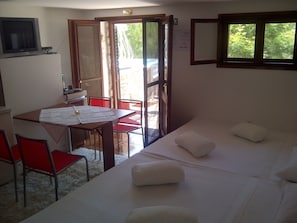 Une chambre avec un lit, une table avec des chaises, un téléviseur et une fenêtre donnant sur un paysage verdoyant.