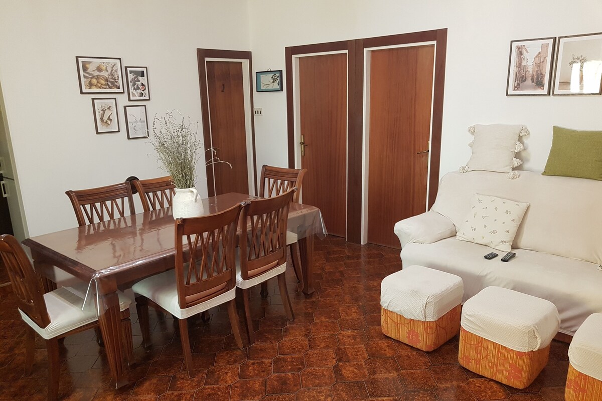 Un comedor con una mesa y sillas de madera, un sofá con cojines y una pequeña mesita auxiliar.
