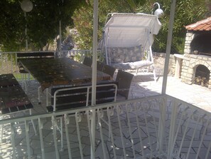 Un patio al aire libre con mesa y sillas, un área de estar techada y una chimenea de piedra.