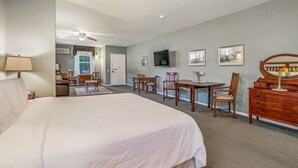 Une chambre d’hôtel avec un grand lit, un bureau, une chaise, une commode, un téléviseur et des tableaux encadrés au mur.