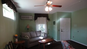 Un salon avec un ventilateur de plafond, un canapé, une table basse et un divan à motifs floraux.