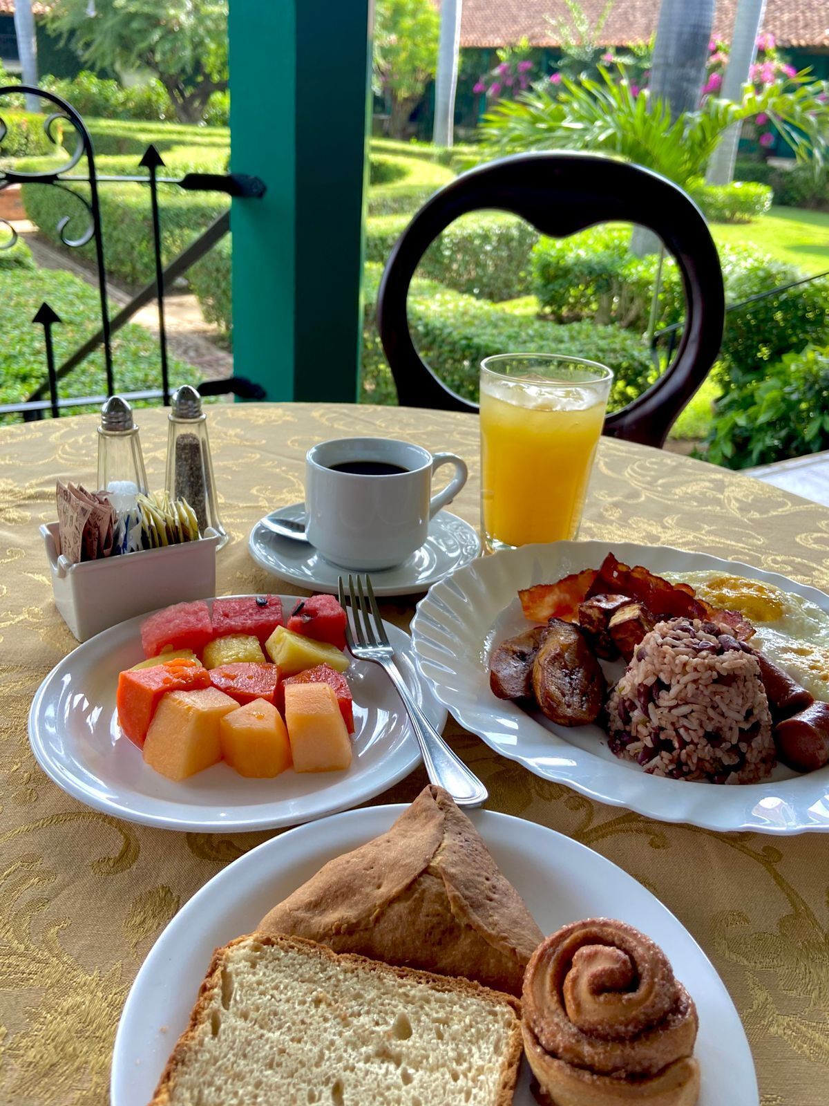 A breakfast setting with plates of food, a cup of coffee, and a glass of orange juice.