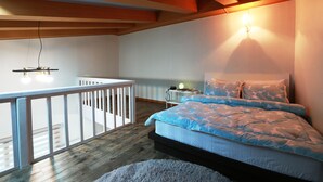 A bedroom with a bed, a desk, and a small table with a lamp. - Tirol Pension (Pyeongchang)